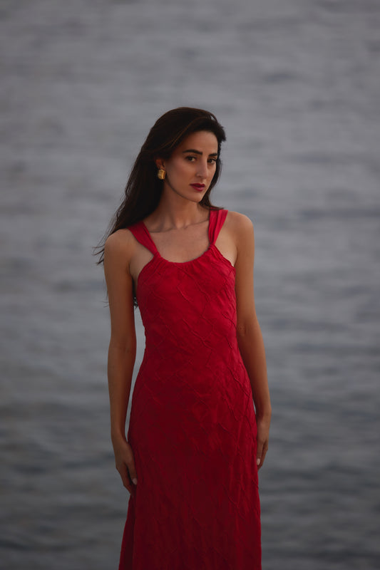 Woman in a Red dress standing against a gray background