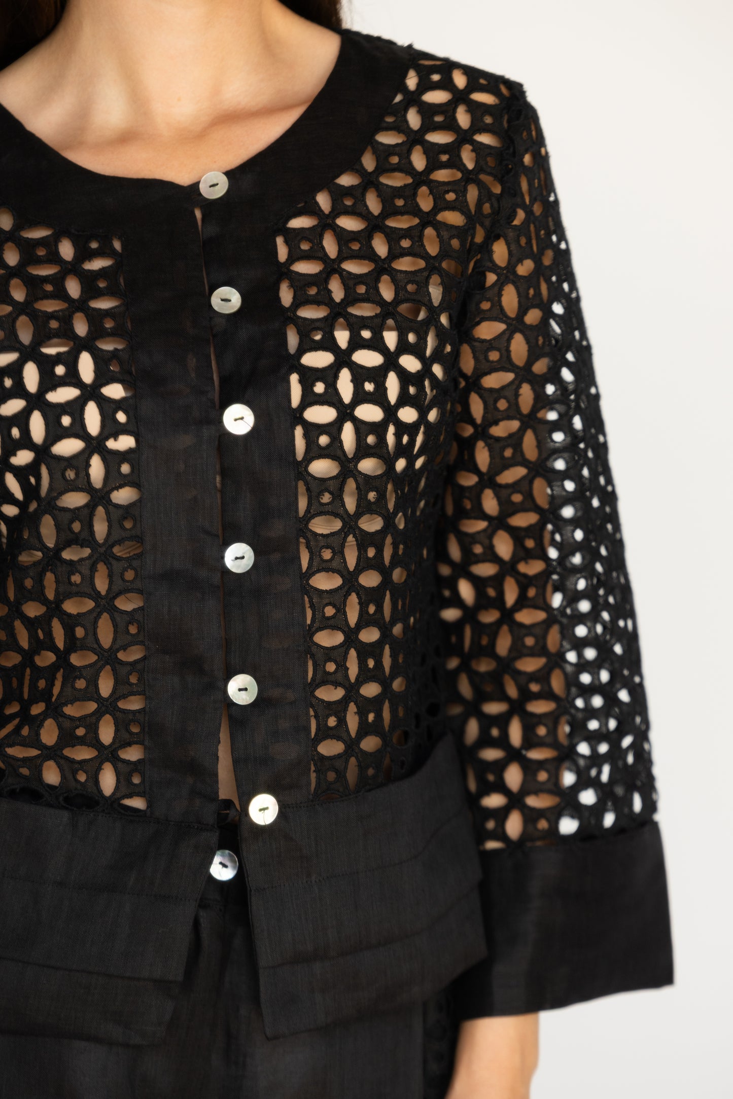 Black lace top with button details on a plain background
