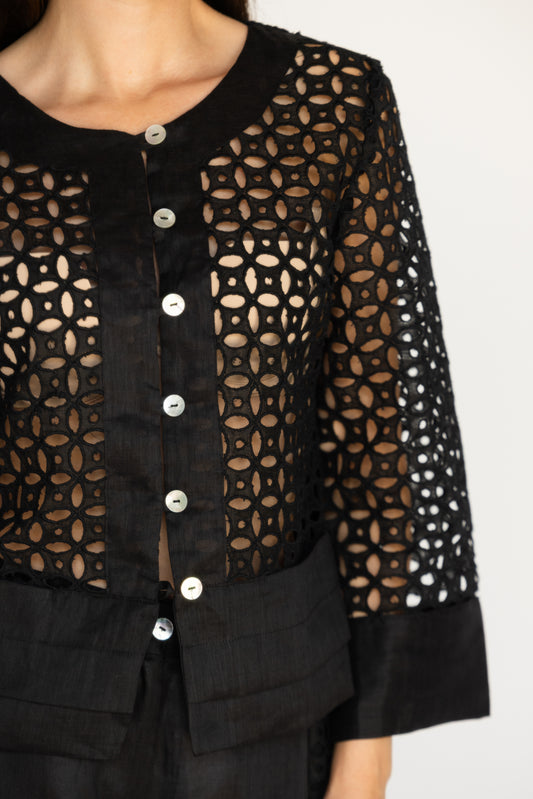 Black lace top with button details on a plain background