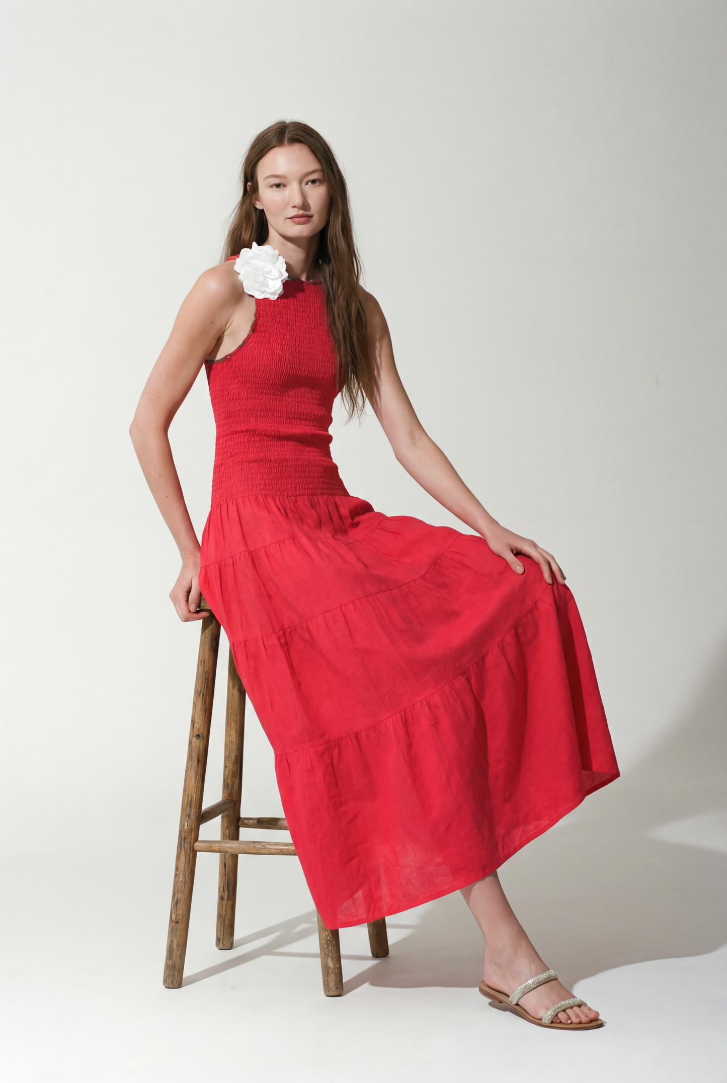 Woman in a Strawberry Red dress standing on a stool against a background