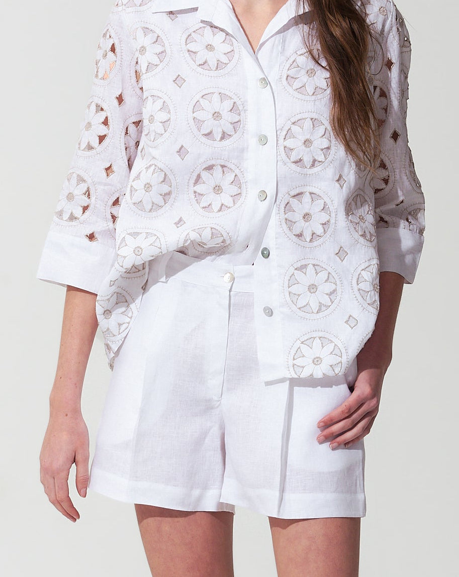 Woman wearing a White outfit with floral patterns on a plain background