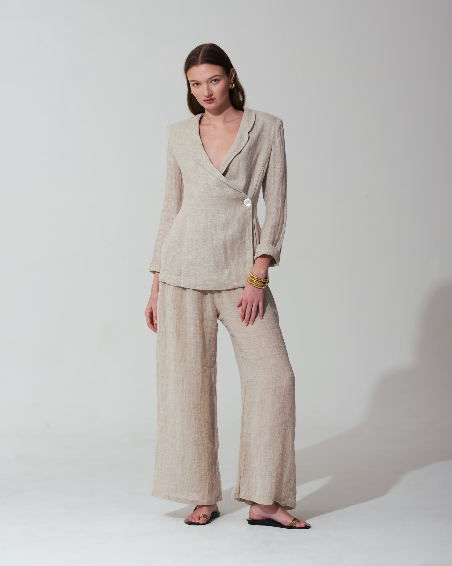 Woman wearing a Sand suit standing against a background