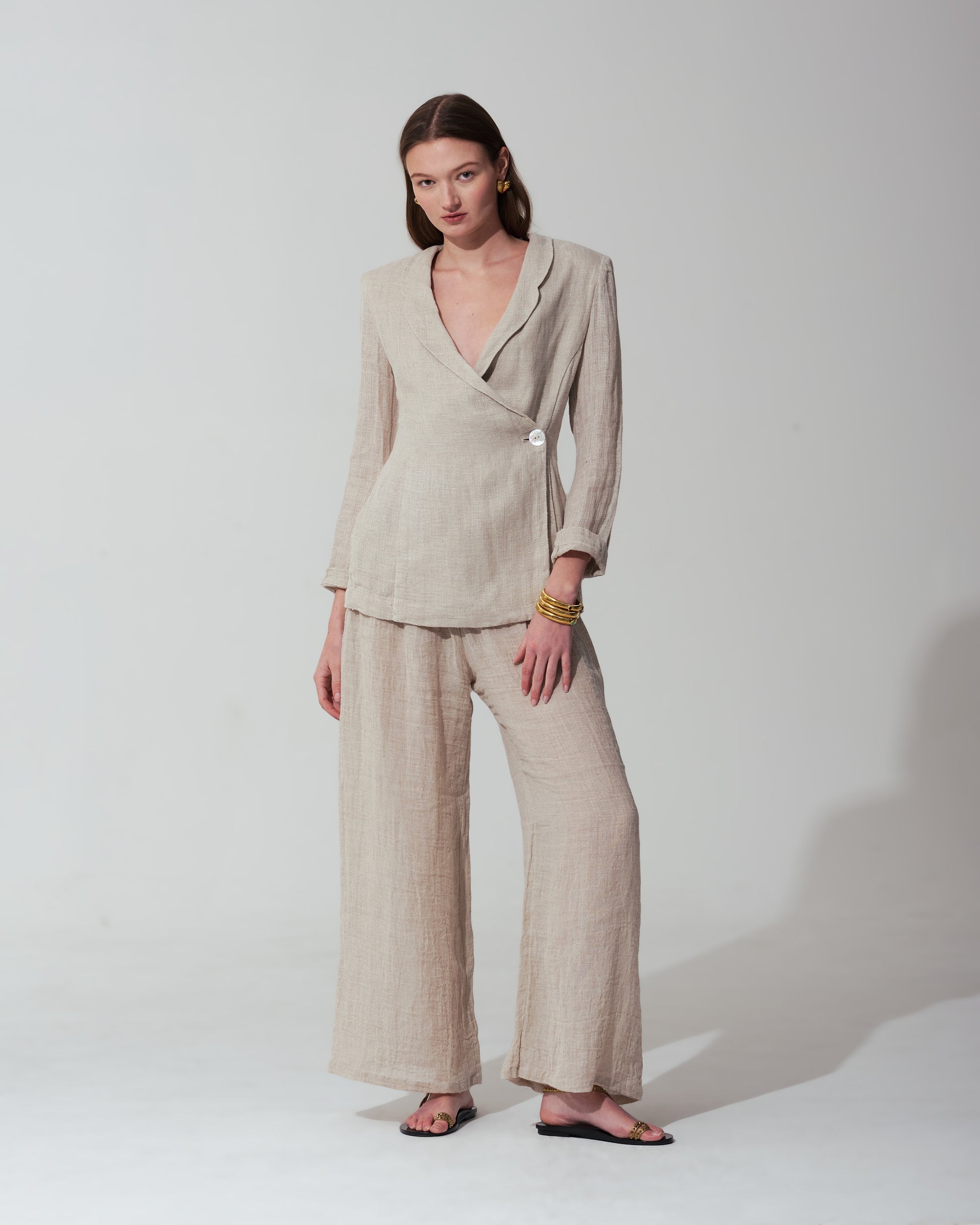 Woman wearing a Sand suit standing against a background