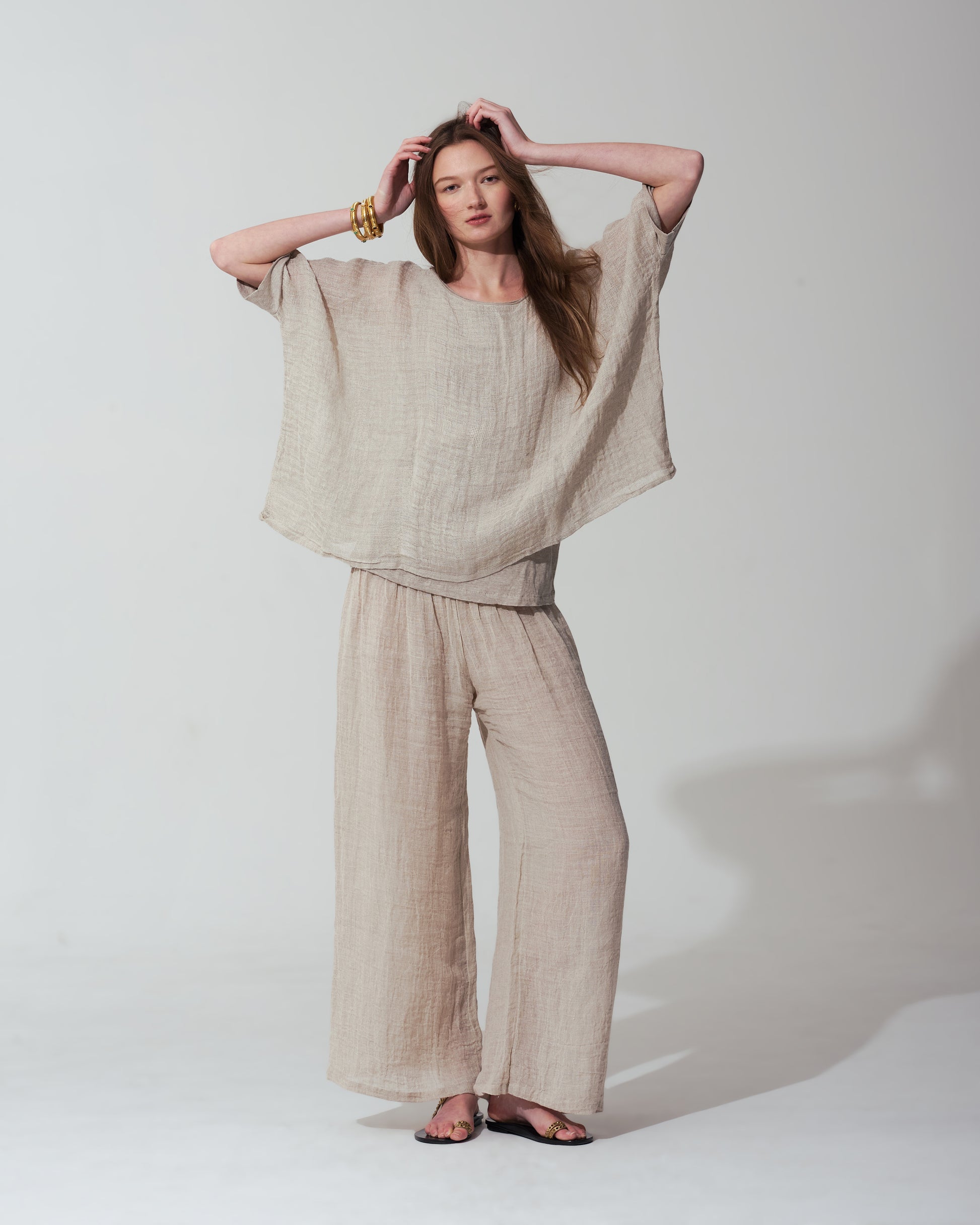 Woman wearing a Sand outfit with wide-leg pants and a top against a  background