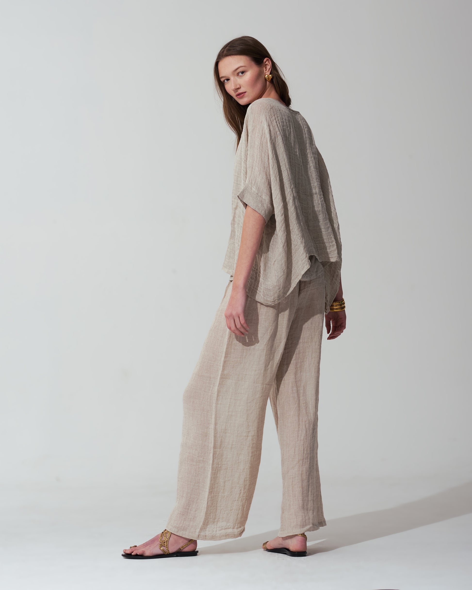 Woman wearing a Sand outfit with a plain background