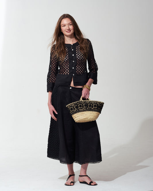 Woman wearing a black outfit with a textured bag on a  background