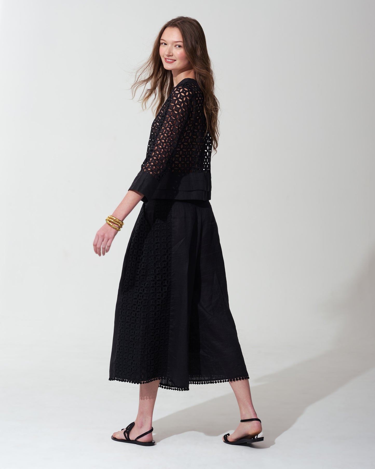 Woman wearing a black outfit with lace details on a background