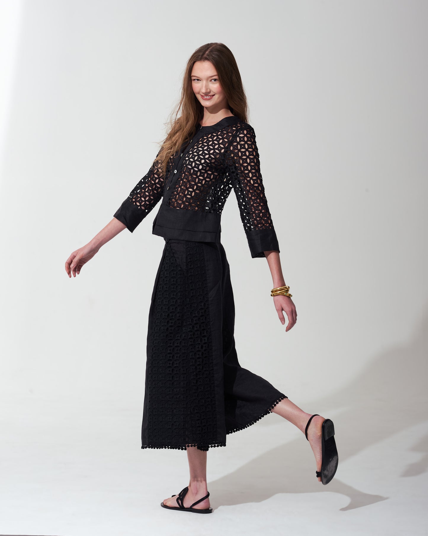 Woman wearing a black outfit with a textured top and skirt on a  background