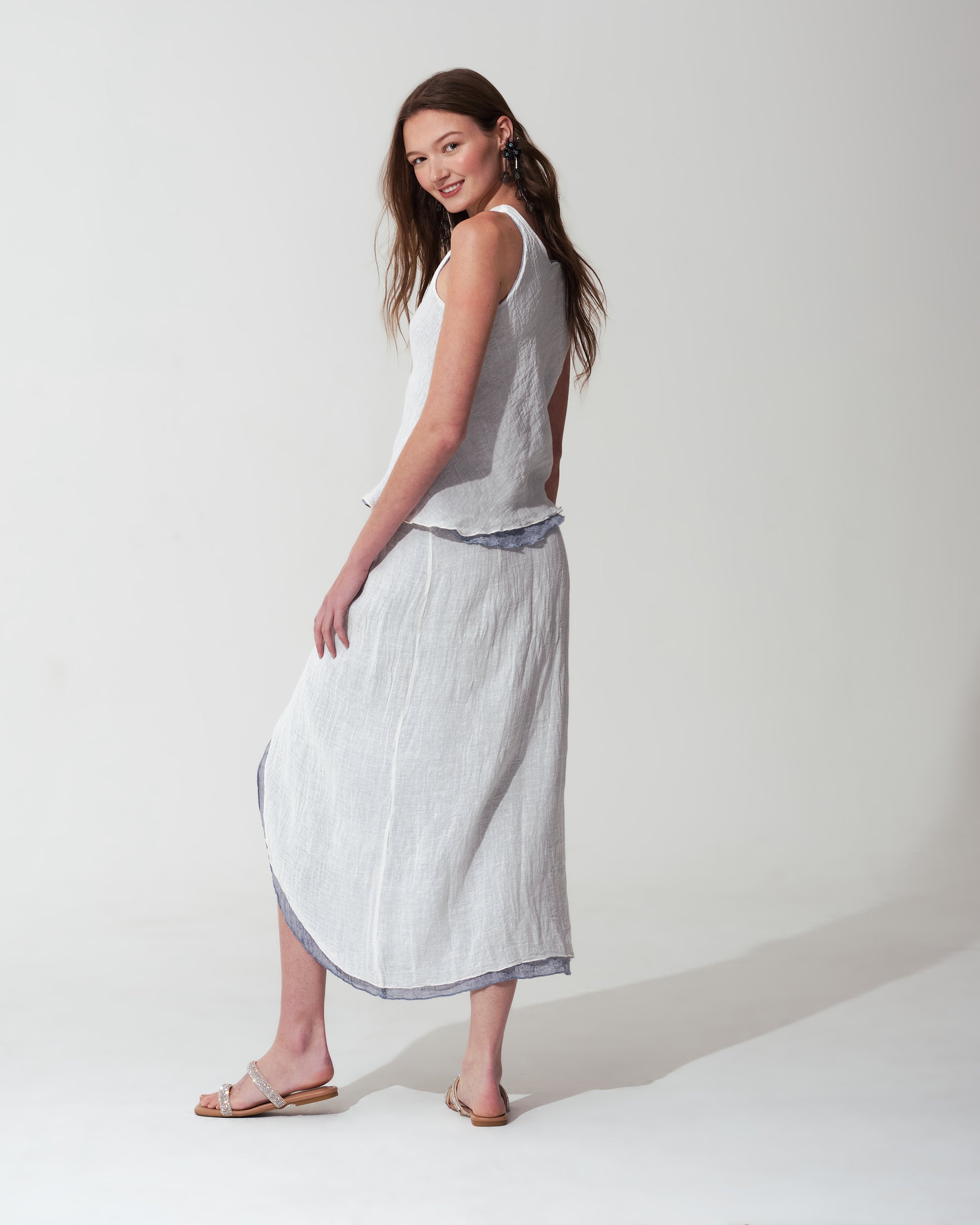 Woman wearing a sleeveless top and White skirt with  trim on background