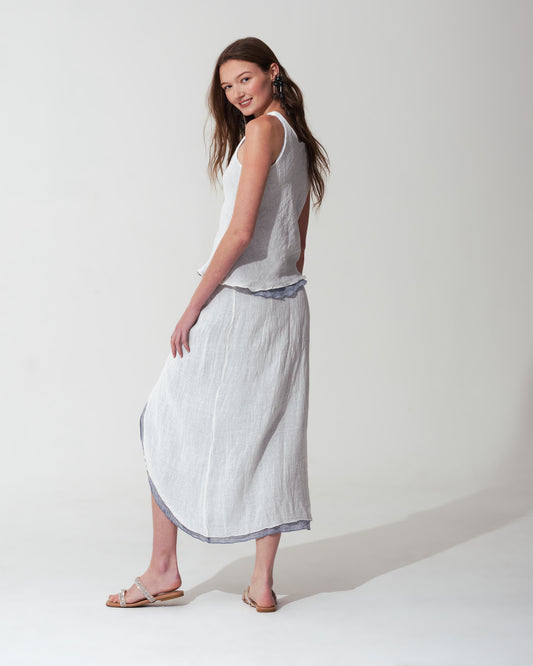 Woman wearing a sleeveless top and White skirt with  trim on background