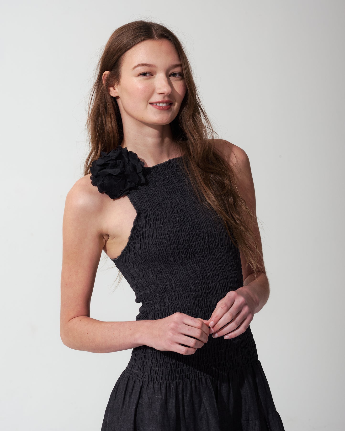 Woman wearing a Dark Denim dress with a flower detail on a plain background