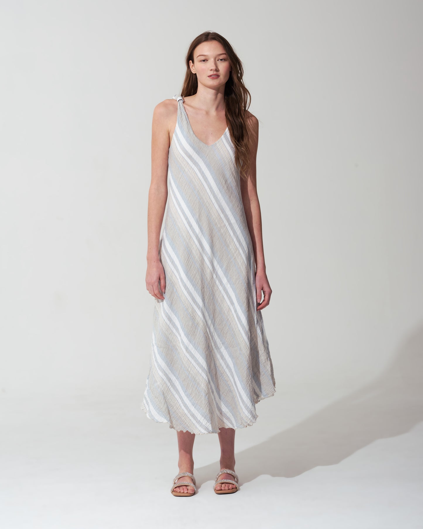 Woman wearing a white and gray striped  blue dress on a white background