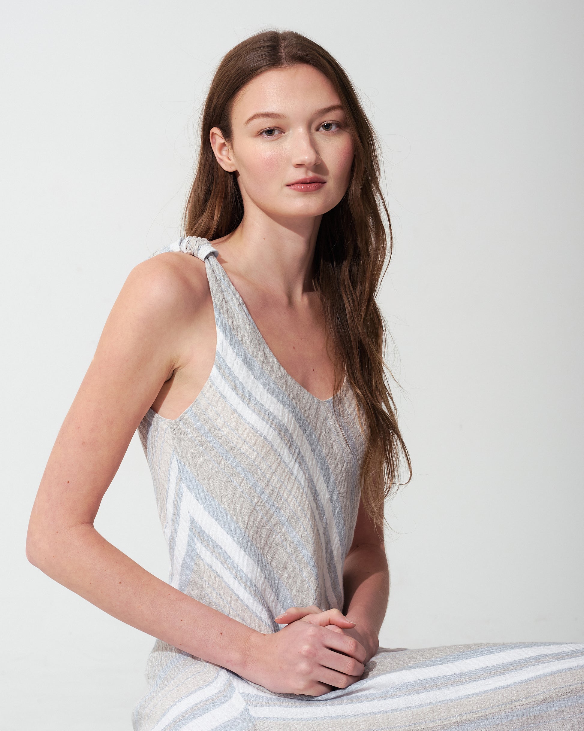 Woman wearing a light-colored striped  blue dress against a plain background