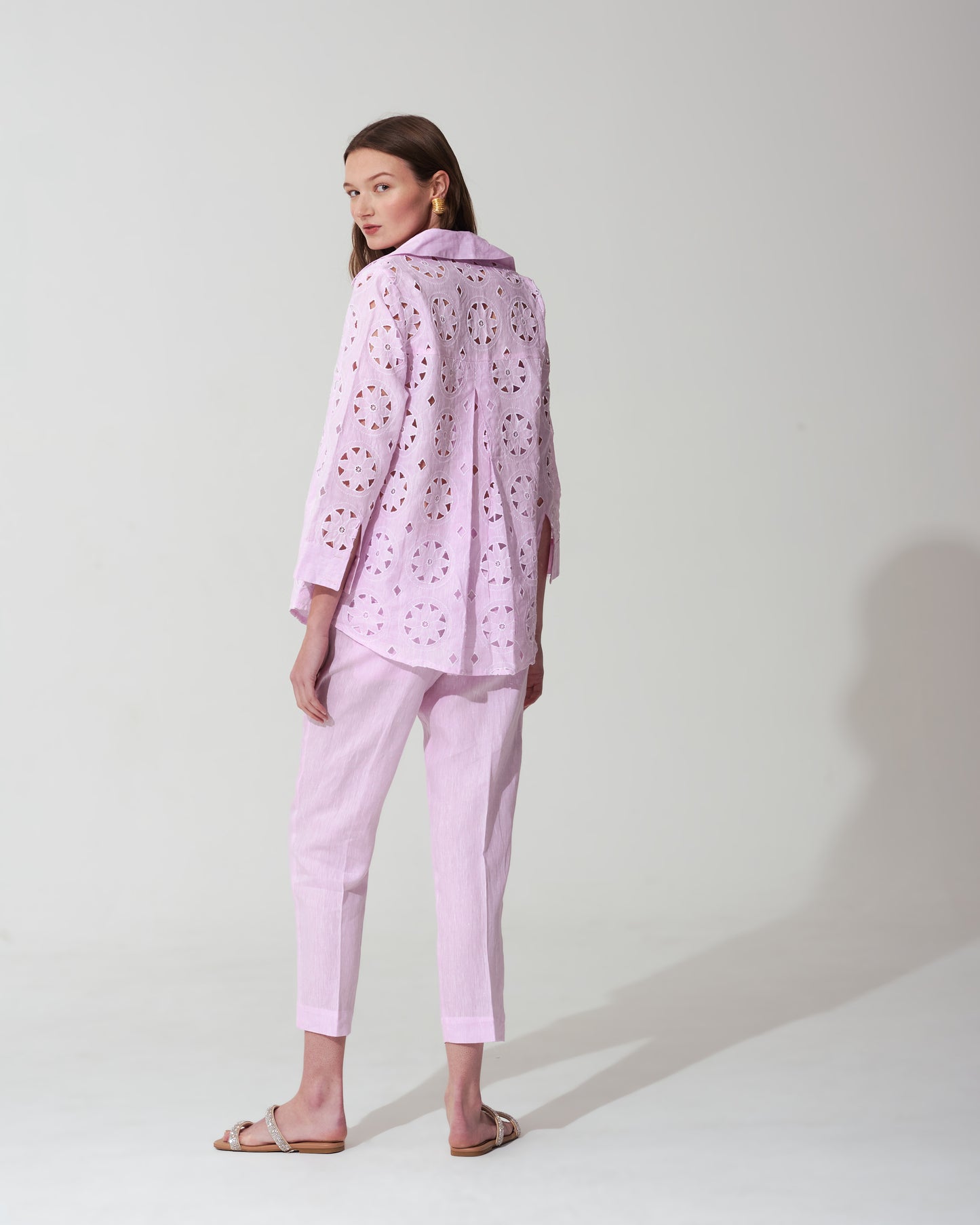 Woman wearing a pastel pink outfit with a matching jacket and pants on a background