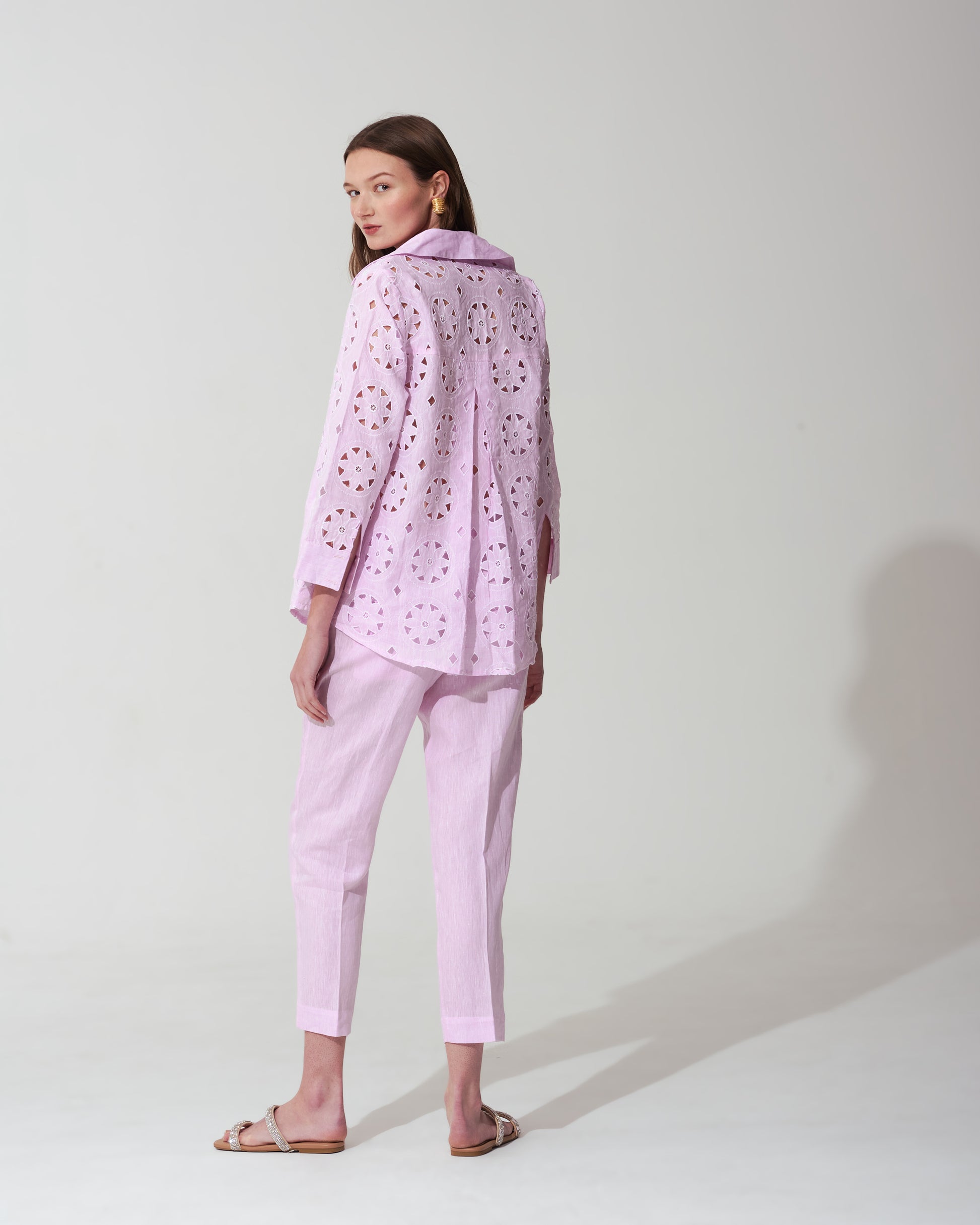 Woman wearing a pastel pink outfit with a matching jacket and pants on a background